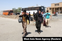 FILE - Afghans walk at the Dowqarun border crossing between Iran and Afghanistan, Razavi Khorasan Province, Iran, August 29, 2021.