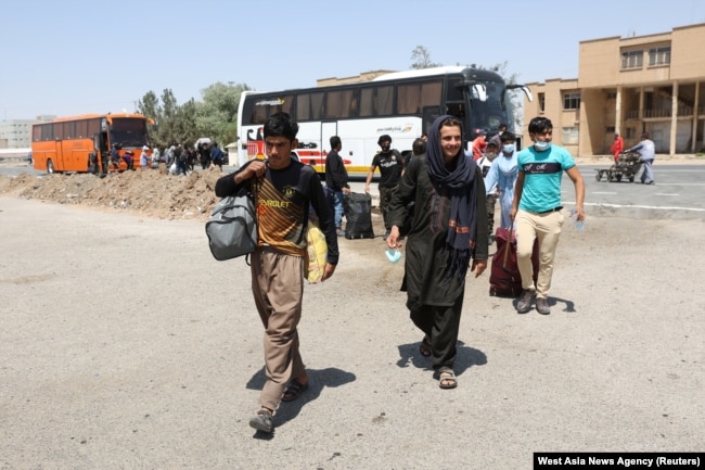 FILE - Afghans walk at the Dowqarun border crossing between Iran and Afghanistan, Razavi Khorasan Province, Iran, August 29, 2021.
