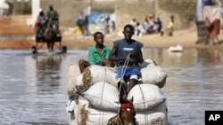 Horse cart drivers transport goods and passengers through deep flood waters in Sicap Mbao, a neighborhood on the outskirts of Dakar, Senegal, Saturday, Sept. 12, 2009