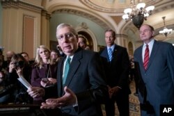 FILE - Senate Majority Leader Mitch McConnell, R-Ky., left, speaks to reporters at the Capitol in Washington, Feb. 12, 2019.