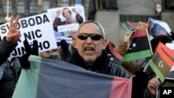 Libyans living in Prague, Czech Republic hold banners and Libya's old national flags as they shout slogans during a protest against the Libyan leader Moammar Gadhafi and condemned the bloody crackdown on the protesters, February 25, 2011