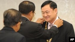 Former Thai Prime Minister Thaksin Shinawatra, right, receives a medal from Cambodia's Prime Minister Hun Sen, center, during the Medal Decoration ceremony at Cambodia Peace Palace in Phnom Penh, Monday, Sept. 19, 2011.