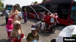 Warga Surabaya, termasuk anak-anak, membawa botol dan gelas plastik untuk ditukarkan dengan tiket Suroboyo bus di stasiun Purbaya (REUTERS/Sigit Pamungkas).