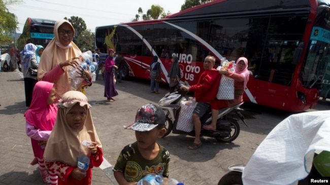 Warga Surabaya, termasuk anak-anak, membawa botol dan gelas plastik untuk ditukarkan dengan tiket Suroboyo bus di stasiun Purbaya (REUTERS/Sigit Pamungkas).
