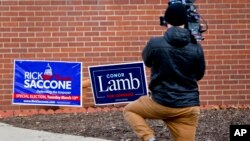 A cameraman films footage of campaign signs outside a polling place for the two candidates running in a special election being held for the Pennsylvania 18th Congressional District, in McKeesport, Pennsylvania, March 13, 2018.