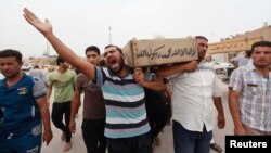 Relatives carry the coffin of an Iraqi police officer killed by militants during a funeral in Najaf, May 20, 2013.