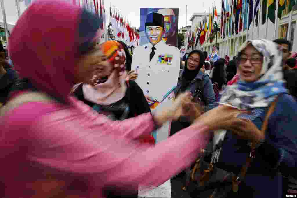Women pose for pictures with a statue of Indonesia's first president Soekarno in Bandung, Indonesia, April 24, 2015.