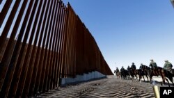 Mounted Border Patrol agents ride along a newly fortified border wall structure, Oct. 26, 2018, in Calexico, California. 