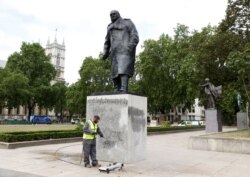 A council employee cleans graffiti from the statue of Winston Churchill at Parliament Square