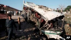 Afghans and security forces inspect damage to a bus after a suicide attack in Jalalabad east of Kabul, April 11, 2016.
