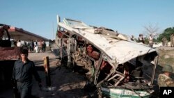 Afghans and security forces inspect damage to a bus after a suicide attack in Jalalabad east of Kabul, Afghanistan, April 11, 2016.