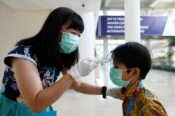 Seorang guru memeriksa suhu soorang murid di sebuah sekolah di Tangerang, 6 Maret 2020. (Foto: Reuters)