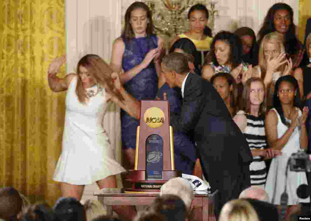 U.S. President Barack Obama hugs UConn women&#39;s basketball coach Geno Auriemma as team star Stefanie Dolson (L) falls off the stage in the background during a ceremony honoring the NCAA basketball champion University of Connecticut Huskies men&#39;s and&nbsp; women&#39;s basketball teams in the East Room of the White House in Washington, June 9, 2014. Dolson was unhurt in the fall.
