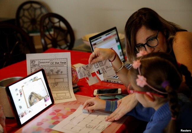 Isabel Martin del Campo, helps her daughter Ines, 6, on her English class, taught by the child's private school, as millions of students returned to classes virtually on Monday after schools were ordered into lockdown in March in Mexico City, Mexico.