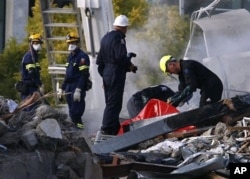 FILE - Emergency workers search through rubble at the site of the CTV building in Christchurch, New Zealand, Feb. 24, 2011, after the city was hit by an earthquake Tuesday.