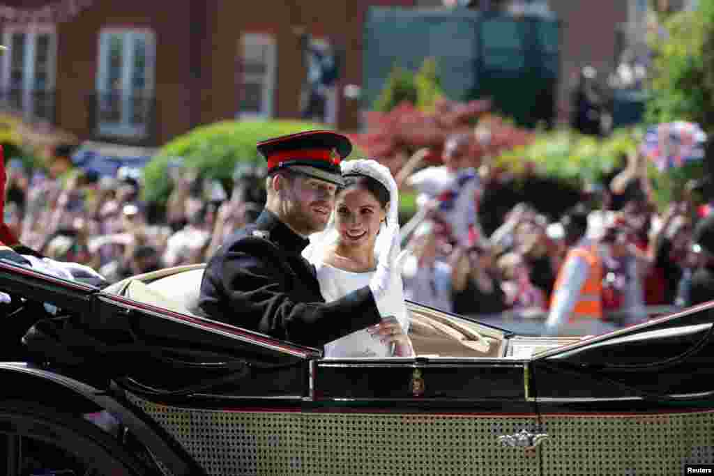 Prince Harry and his wife, Meghan Markle, wave as they ride a horse-drawn carriage after their wedding ceremony at St George's Chapel in Windsor, Britain, May 19, 2018.