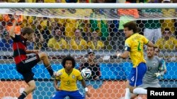 Germany's Thomas Mueller (L) scores the team's first goal next to Brazil's David Luiz (4) as Marcelo (6) and Brazil goalkeeper Julio Cesar (12) watch during their 2014 World Cup semi-finals at the Mineirao stadium in Belo Horizonte July 8, 2014. 