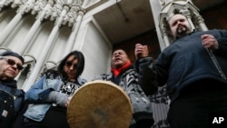 Native American protestors hold hands with parishioner Nathanial Hall, right, during a group prayer outside the Catholic Diocese of Covington Tuesday, Jan. 22, 2019, in Covington, Ky. (AP Photo/John Minchillo)