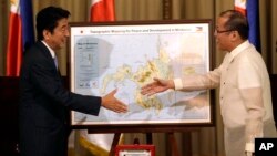 ທ່ານ Shinzo Abe ນາຍົກລັດຖະມົນຕີຍີ່ປຸ່ນ​ (ຊ້າຍ) ແລະທ່ານ Benigno Aquino III ປະທານາທິບໍດີຟີລິບປິນ ຈັບມືກັນ ລຸນຫລັງທີ່ທ່ານ Abe ໄດ້ເອົາພາບແຜນທີ່ ໝູ່ເກາະ Mindanao ຂອງຍີ່ປຸ່ນມາໃຫ້ເບິ່ງ ໃນຕອນປິດທ້າຍ ກອງປະຊຸມຖະແຫລງການຮ່ວມ ທີ່ທໍານຽບປະທານາທິບໍດີ Malaca ໃນກຸງມະນີລາ, ໃນວັນທີ 27 ກໍລະກົດ.