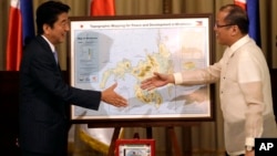 Japanese Prime Minister Shinzo Abe, left, and Philippine President Benigno Aquino III shake hands after Abe presented him with a topographical map of the country's third largest island of Mindanao, July 27, 2013.