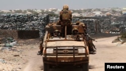 Kenya Defence Force (KDF) soldiers, serving in African Union Mission in Somalia (AMISOM), patrol past stockpiles of charcoal near the Kismayo sea port town (2013 photo)