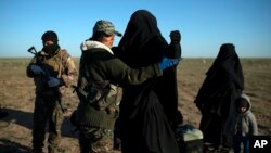 FILE - A woman is frisked by a U.S.-backed Syrian Democratic Forces (SDF) fighter at a screening area after being evacuated out of territory held by Islamic State group militants, in the desert outside Baghuz, Syria, March 1, 2019.