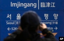 A woman takes a photo in front of a signboard showing the distance to North Korea's capital Pyongyang and to South Korea's capital Seoul from Imjingang Station in Paju, South Korea, Nov. 24, 2018. The United Nations Security Council granted an exemption to sanctions that will allow surveys on North Korean railroad sections the Koreas want to connect with the South.