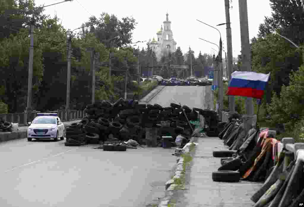 Sebuah mobil melintasi barikade berhiaskan bendera nasional Rusia di jalan yang mengarah ke Slovyansk, Ukraina timur (13/5). (AP/Darko Vojinovic)