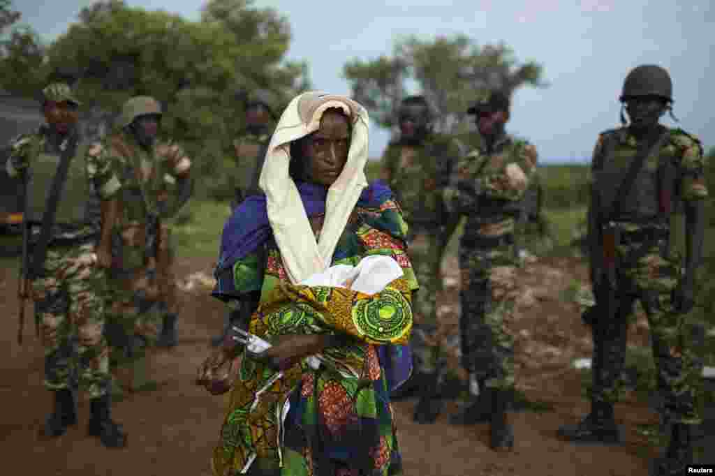 Thân nhân bế một em bé của cặp song sinh mà một phụ nữ vừa sinh ra trước khi khởi hành về phía biên giới Chad, được quân đội Liên minh Châu Phi hộ tống tại thị trấn Kaga Bandoro phía bắc, Cộng hòa Trung Phi.
