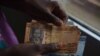 FILE - A person counts South Sudanese pounds in Juba on April 28, 2016. 