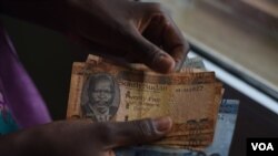 FILE - A person counts South Sudanese pounds in Juba on April 28, 2016. 