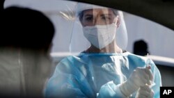 A medical staffer performs tests for COVID-19 at a drive-through at Rome's Leonardo Da Vinci airport, Friday, Oct. 9, 2020. Italy’s new confirmed caseload Friday passed 5,372, the highest levels since March. (Cecilia Fabiano/LaPresse via AP)