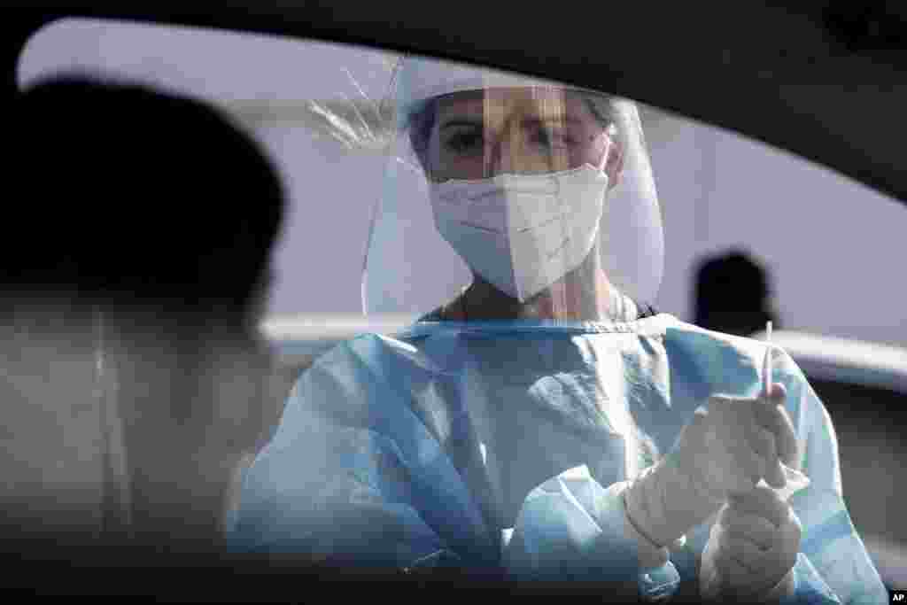 A medical staffer performs tests for COVID-19 at a drive-through at Rome&#39;s Leonardo Da Vinci airport, Friday, Oct. 9, 2020. Italy’s new confirmed caseload Friday passed 5,372, the highest levels since March. (Cecilia Fabiano/LaPresse via AP)