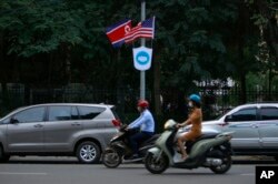 People ride mopeds past flags of North Korea and the U.S flown on a street in Hanoi, Vietnam, Feb.19, 2019.