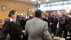 Onesphore Rwabukombe, 53, is photographed by media as he waits for the beginning of his trial at a court in Frankfurt, central Germany, 18 Jan 2011