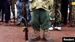 FILE - A former child soldier holds a gun as he and others participate in a child soldiers' release ceremony, outside Yambio, South Sudan, Aug 7, 2018.