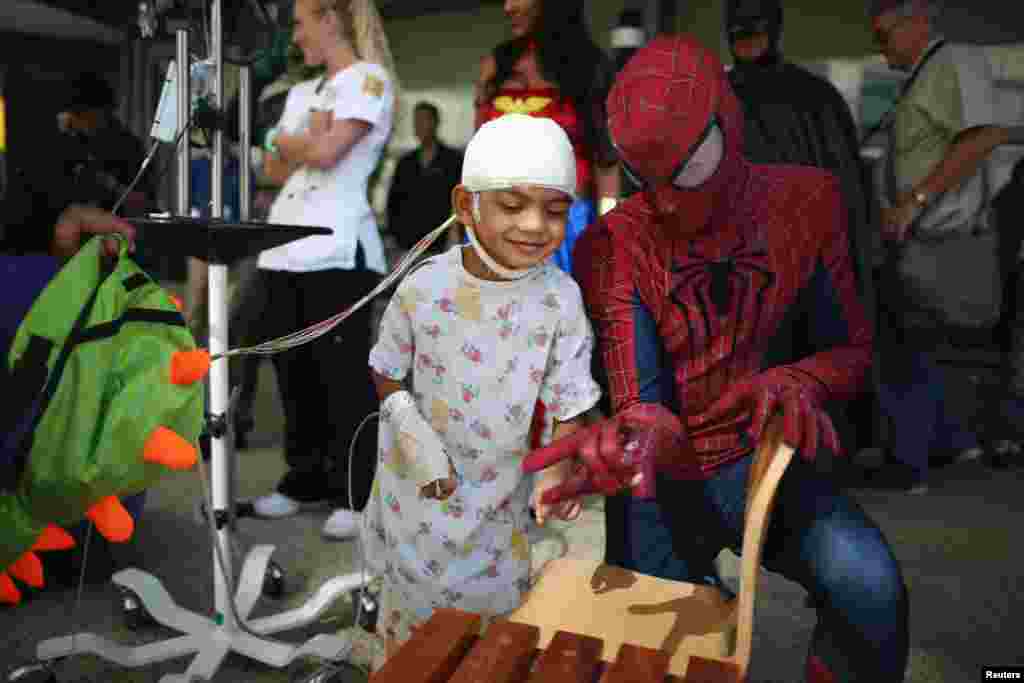 Mattel Children&#39;s Hospital UCLA patient Gael Martin, 5, (L) meets a window washer dressed as Spider-Man in Los Angeles, California, Sept. 14, 2016.