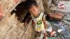 FILE - A boy plays in front of his house in Andong village, on the outskirts of Phnom Penh.