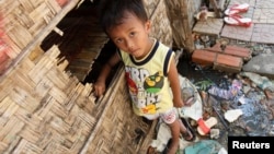FILE - A boy plays in front of his house in Andong village, on the outskirts of Phnom Penh.
