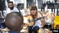 Musician Kelly Grevler gives guitar lessons to underprivileged children on a sidewalk in central Johannesburg. (D. Taylor/VOA)