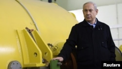 Israel's Prime Minister Benjamin Netanyahu stands next to a free-electron laser (FEL) during a visit to the Ariel University Center in the West Bank Jewish settlement of Ariel, January 8, 2013.