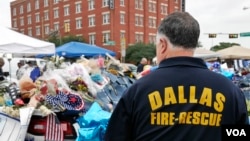 A Dallas firefighter pays respects at the makeshift memorial for fallen officers outside Dallas police headquarters in Texas, July 11, 2016. (M. O'Sullivan/VOA)
