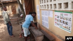 Des électeurs togolais examinent une liste électorale devant un bureau de vote dans le quartier de Be à Lomé le 20 décembre 2018 lors de la procédure de vote pour les élections législatives.