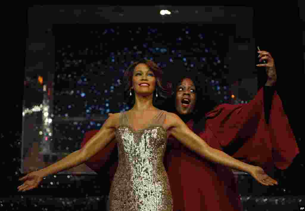 A member of a gospel choir pretends she takes a picture of herself with the wax figure of late U.S. singer Whitney Houston, as she poses for the photographers at Madame Tussauds in London, Britain.