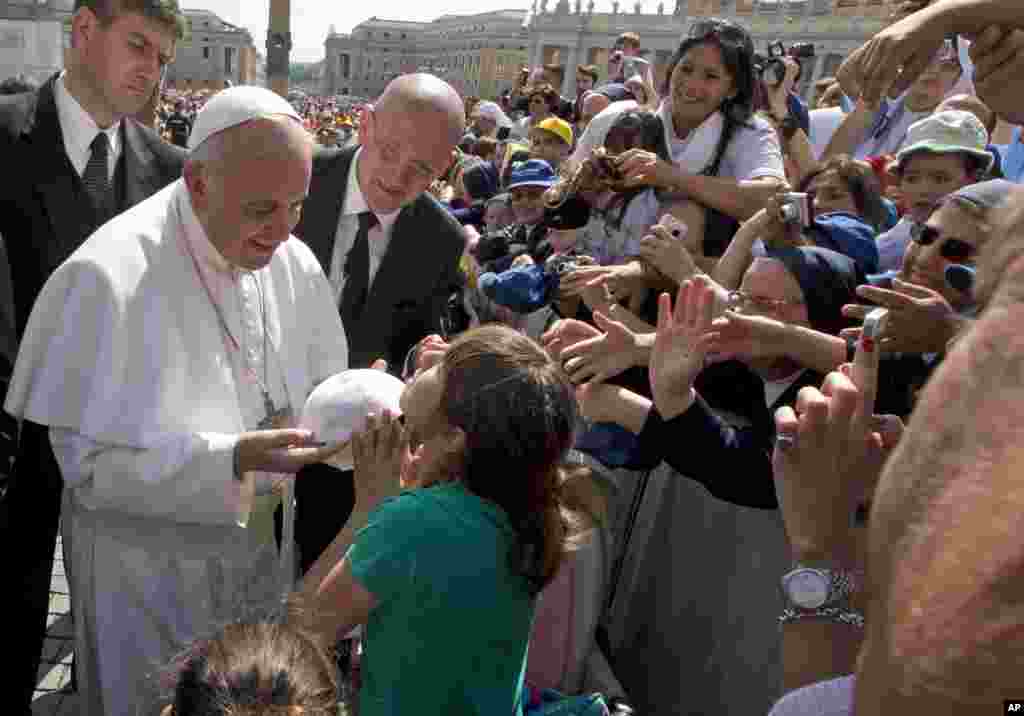 Pope Francis exchanges skull caps with a young girl in St. Peter&#39;s Square at the Vatican. 