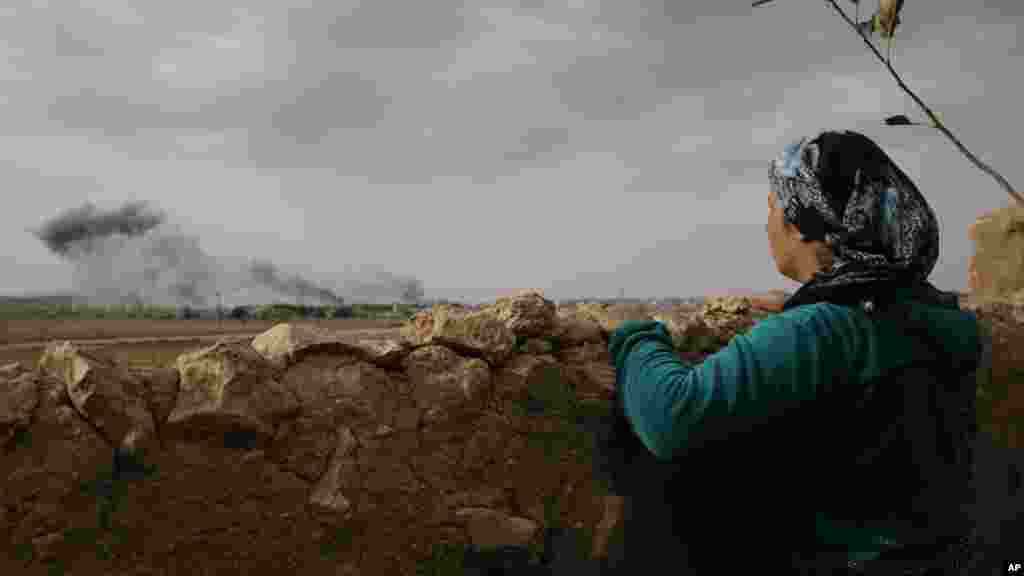 Une Kurde Turque, &nbsp;débout à Muritpinar, dans les périphéries de Suruc, à la frontière Turco-Syrienne, contemple la fumée venant des flammes causées par les frappes au cours des combats entre les combattants de l&rsquo;Etat islamique et les forces kurdes, en Syrie, dimanche le 12 octbre 2014. (AP Photo/Lefteris Pitarakis) 