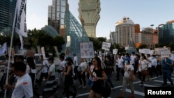FILE - Workers from Macau's six major casinos, led by union "Forefront of Macau Gaming", march past Casino Lisboa during a demonstration in Macau, Aug. 25, 2014. 
