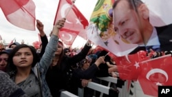 Supporters wave flags as Turkey's President Recep Tayyip Erdogan delivers a speech during a rally of supporters a day after the referendum, at his palace, in Ankara, April 17, 20