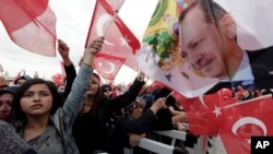 FILE - Supporters wave flags as Turkey's President Recep Tayyip Erdogan delivers a speech during a rally of supporters a day after the referendum, at his palace, in Ankara, April 17, 2017.