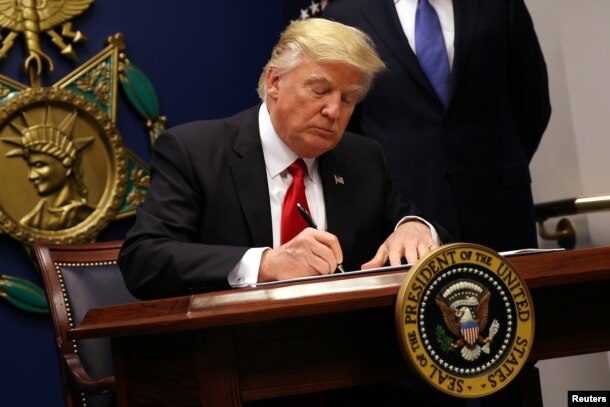 U.S. President Donald Trump signs an executive order imposing immigration restrictions for certain countries, at the Pentagon, outside Washington, Jan. 27, 2017. A former Homeland Security official argues that blanket restrictions will do little to achieve their intended effect.